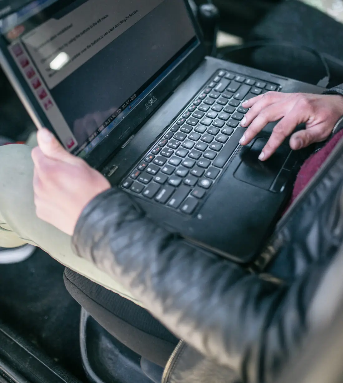 Persona usando una notebook de diagnóstico dentro de un auto.