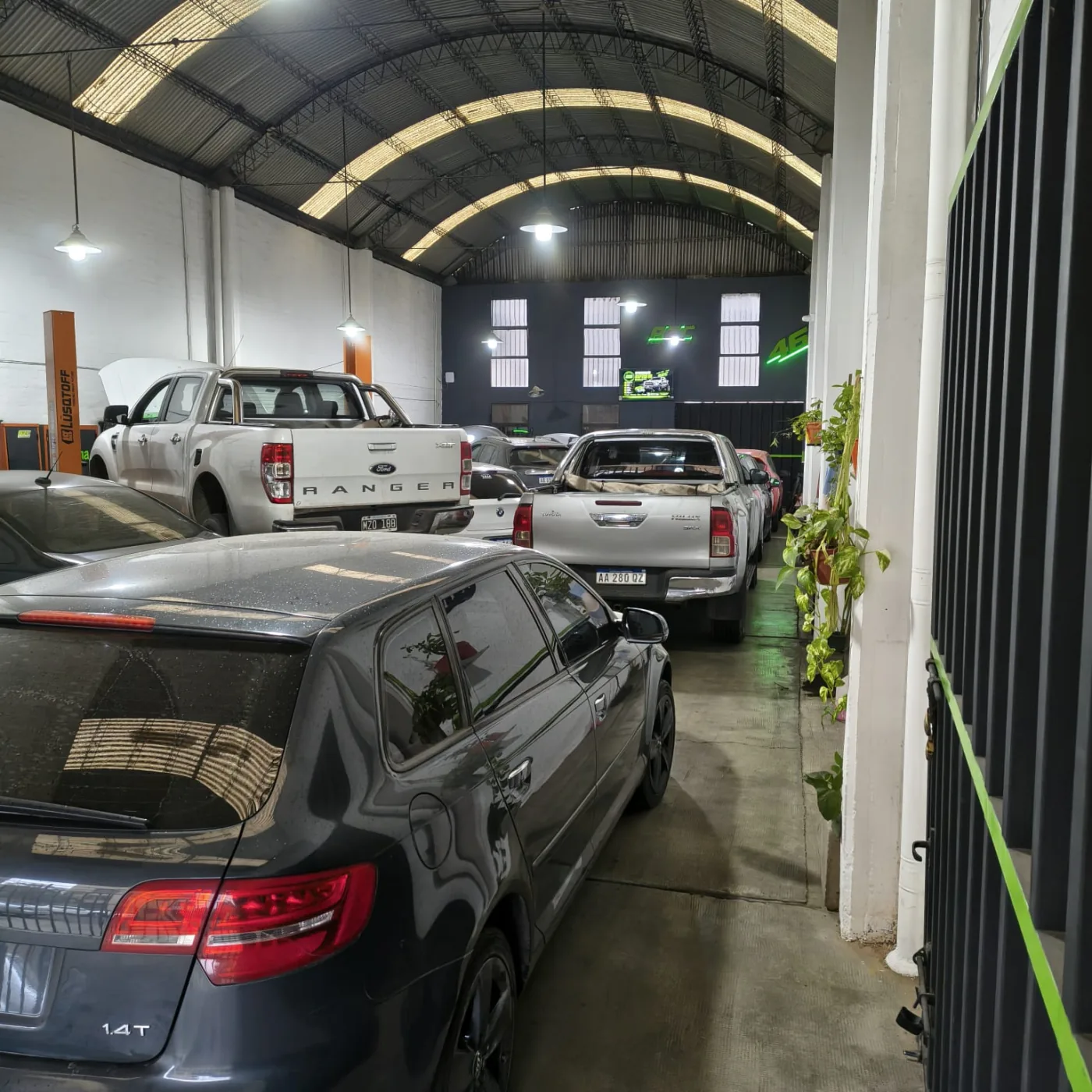 Interior del taller Azcona con vehículos y la identidad de AZC Performance al fondo.